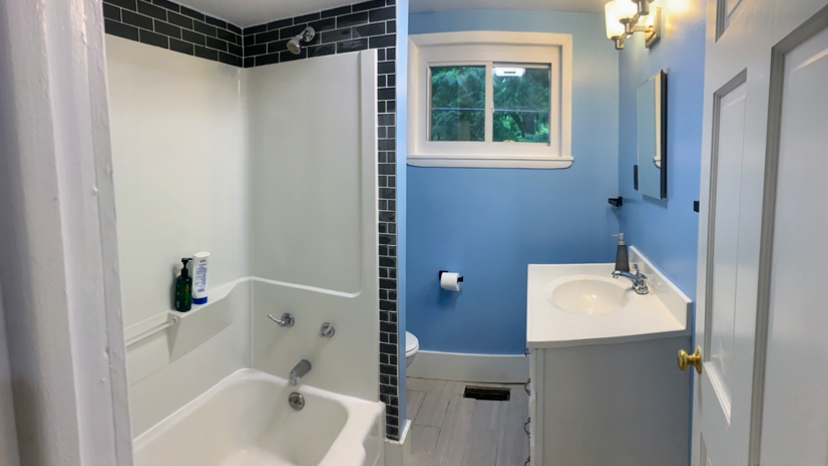 A recently completed bathroom remodel by Columbus Handy Guys, with a black-tile-accented tub surround and new vanity